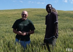 two men standing in field of grain; photo by Foods Resource Bank