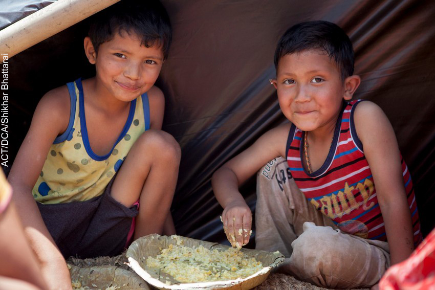 Young boys in temporary shelter enjoy a meal provided by ACT Alliance partners in Nepal 