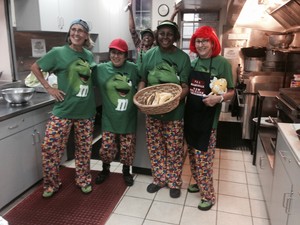 four ladies dressed alike in the kitchen with fun shirts and hats