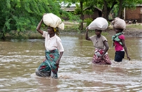 Women wade in the water carrying supplies on their heads