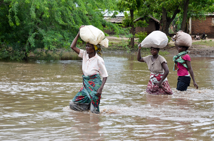Women wade in the water carrying supplies on their heads