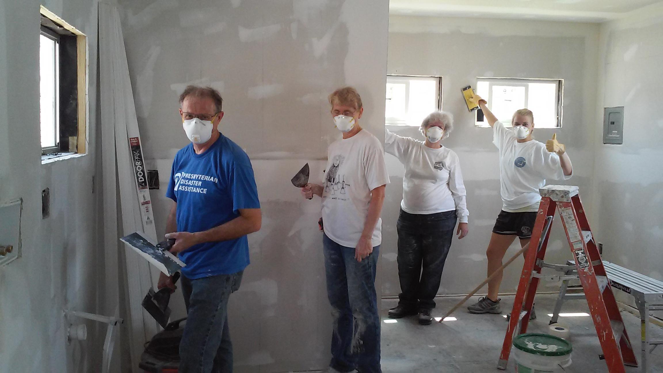 four volunteers working with drywall