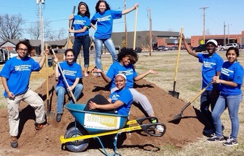 volunteers on dirt pile with wheelbarrow